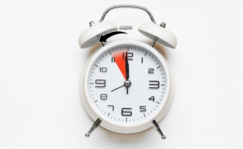 Alarm clock with arrow showing daylight saving time clock change