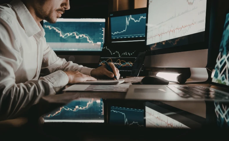 Analyst reviewing market charts at a trading desk