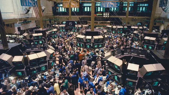 Crowded NYSE trading floor with banks of monitors and traders, representing the chaotic conditions on October 16, 1987, the triple witching Friday before Black Monday