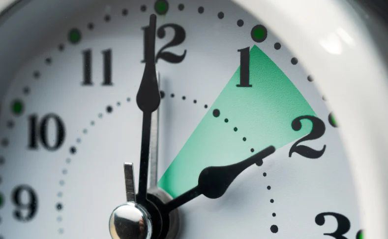 Close-up of a clock face with the hour hand highlighted between 1 and 2.