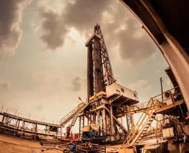 Oil drilling rig at dusk under a cloudy sky, representing the physical crude oil market behind WTI and Brent futures trading