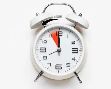 Alarm clock with arrow showing daylight saving time clock change