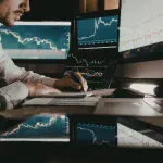 Analyst reviewing market charts at a trading desk