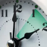 Close-up of a clock face with the hour hand highlighted between 1 and 2.