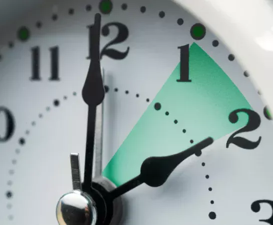Close-up of a clock face with the hour hand highlighted between 1 and 2.